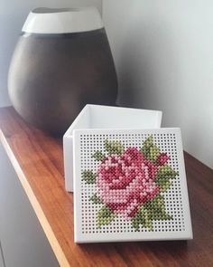 a white box with a pink flower on it next to a black vase