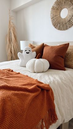 a white bed topped with lots of pillows next to a wall mounted clock and wicker wreath