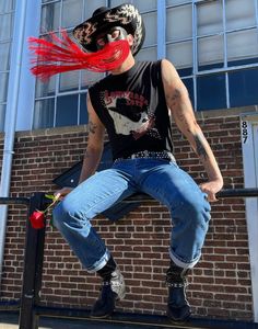 a man with red hair sitting on top of a metal rail next to a brick building