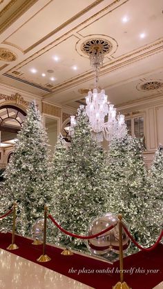 a christmas tree in the middle of a room with chandelier and red carpet