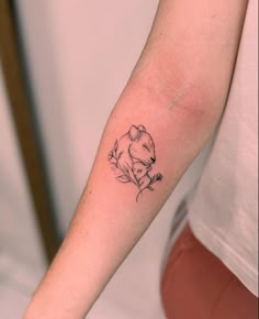 a woman's arm with a small tattoo of a koala and leaves on it