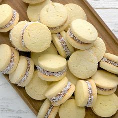 a wooden tray filled with lots of cookies on top of a white tablecloth covered in powdered sugar