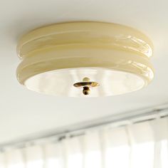 a ceiling light that is hanging from the ceiling in a room with white walls and curtains