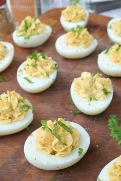 deviled eggs with mayonnaise and parsley sprinkled on them sitting on a cutting board