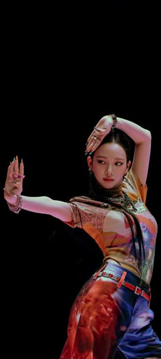 a woman is dancing with her arms stretched out and hands in the air while wearing colorful clothing