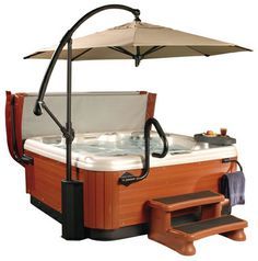 a hot tub with an umbrella over it next to a step stool and towel rack