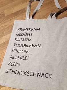 a tote bag with the names of different languages on it sitting on a wooden floor