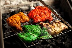 several different colored meats cooking on a grill