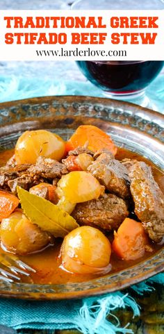 traditional greek beef stew with potatoes and carrots in a brown bowl next to a glass of red wine