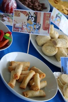 several plates with food items on them sitting on a blue tablecloth covered table cloth