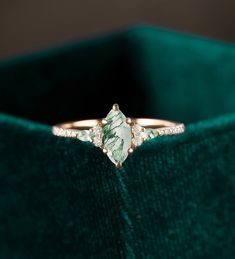 a close up of a ring on a green velvet box with diamonds in the middle