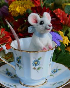 a little mouse sitting in a tea cup