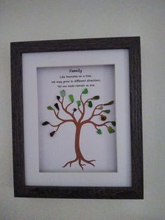 a family tree with green leaves in a black frame on the wall above a toilet