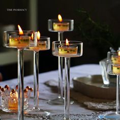 candles are lit in glass vases on a table