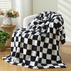 a black and white checkered blanket sitting on top of a chair next to a potted plant