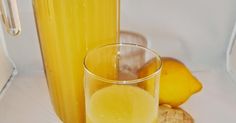 a glass of lemonade next to a bottle and some cookies on a white surface