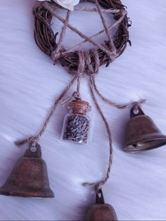 three bells hanging from a rope with some flowers on top of it and two small glass bottles in the middle