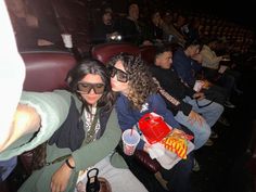 two women sitting next to each other in front of an audience at a movie theater