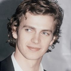 a young man in a suit and tie smiling at the camera with his eyes wide open