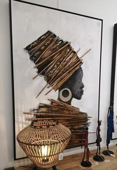 an art piece is displayed in front of a painting on the wall with bamboo sticks sticking out of it