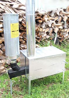 a large metal box sitting on top of a grass covered field next to stacks of wood