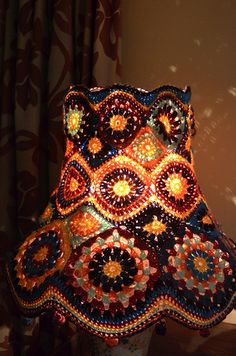 a crocheted lamp shade is sitting on a table