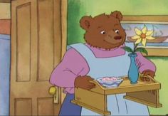 a cartoon bear holding a blue vase with a flower in it's hand while standing next to a table