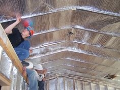 two men are working on the roof of a building with tin foil covering them and one man is holding a skateboard