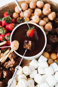 a bowl filled with chocolate, marshmallows and strawberries