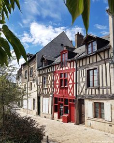 an old building with red and white paint on it's side in the middle of town