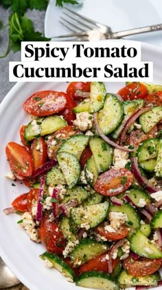 a white plate topped with cucumber, tomatoes and onions next to silverware