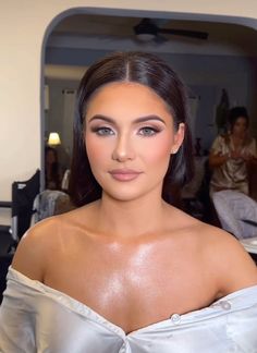 a woman in a white dress posing for the camera with her hair pulled back and eyes closed