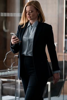 a woman in a suit is looking at her cell phone