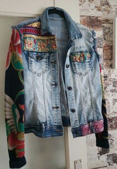 a jean jacket hanging on a door with an open pocket and colorful print lining the back