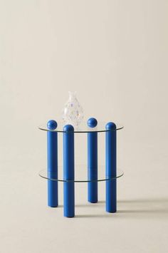 a glass table with three blue cylinders around it and a clear object in the middle