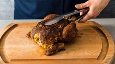 a person cutting up some food on top of a wooden board with a knife in it