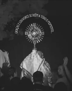 a black and white photo of people raising their hands in front of a priest's altar