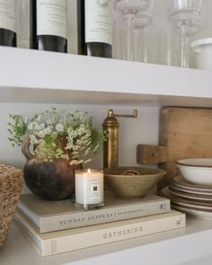 a shelf filled with books and candles next to wine glasses on top of each other