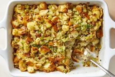 a casserole dish with stuffing in it and a serving spoon on the side