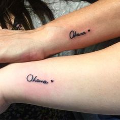 two people with matching tattoos on their arms, one is holding the other's arm