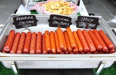 there are many hot dogs and chips on the grill at this outdoor party, including one for sale