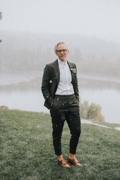 a man standing on top of a lush green field next to a lake in the fog