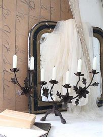 a table topped with a vase filled with flowers next to a mirror and candle holders