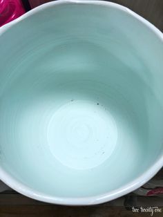 a large white bowl sitting on top of a wooden table next to a pink container