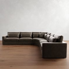 a large sectional couch sitting on top of a wooden floor next to a white wall