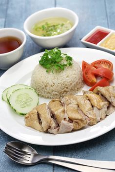 a white plate topped with rice and meat next to bowls of sauces and vegetables