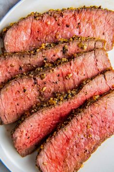 sliced steak on a white plate with seasoning sprinkled around the top and sides