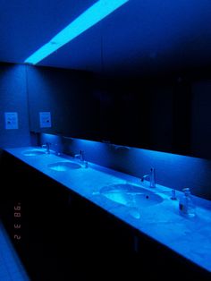 a bathroom with two sinks and blue lights