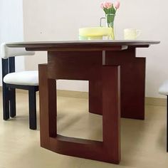 a dining table with two chairs and a vase filled with flowers on top of it