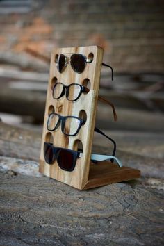 three pairs of sunglasses are placed in a wooden display case on top of a rock